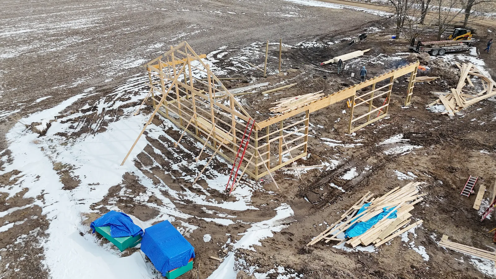Owosso barn build — early framing phase, oblique angle showing structure and site conditions